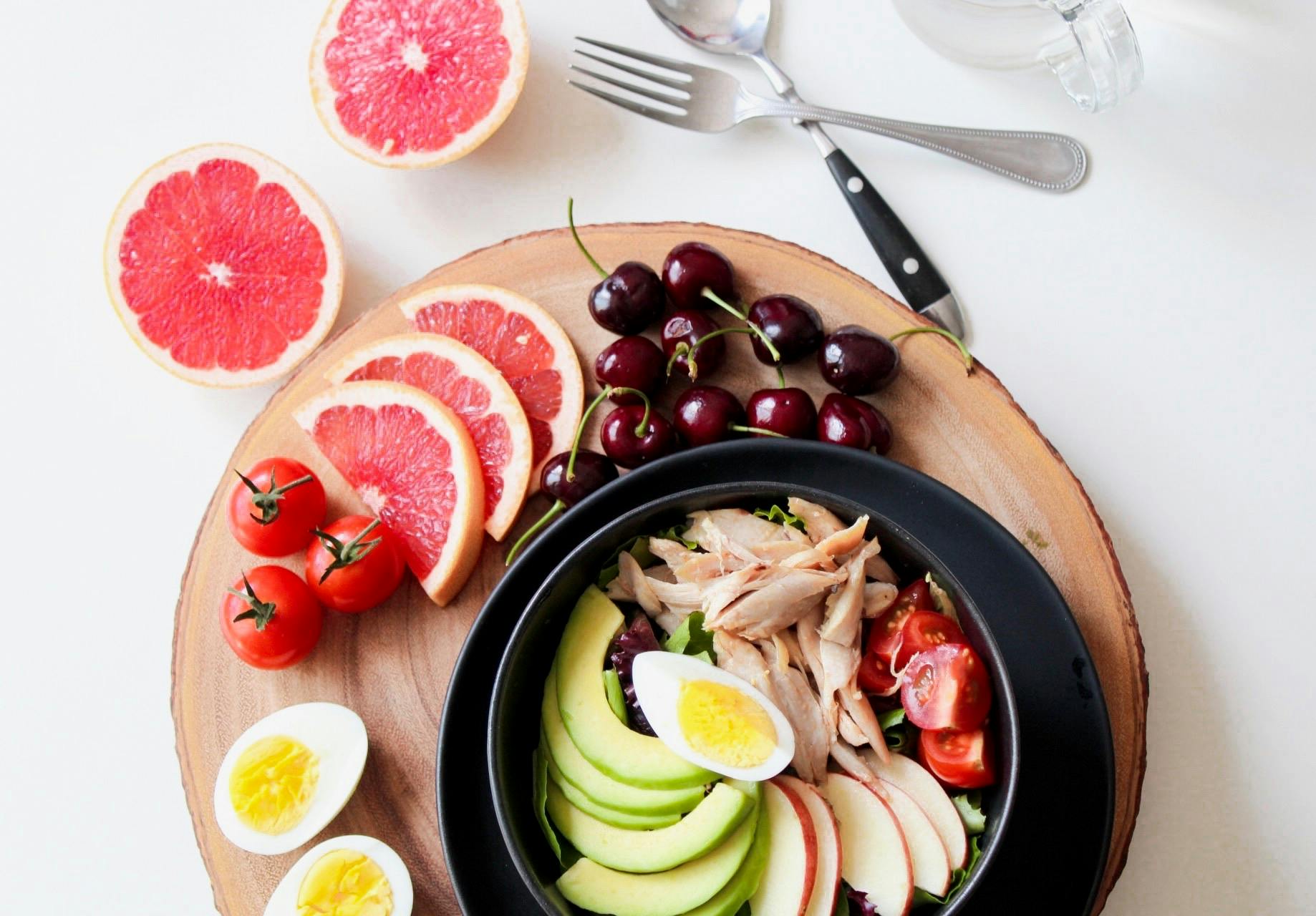 Fruit, boiled eggs, avocado, and chicken displayed in a bowl