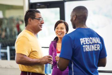 A man and woman laugh with their personal trainer