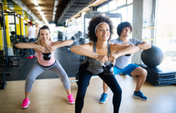 three people lifting kettle bells in a fitness class