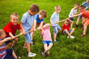 A group of young boys playing tug of war on a grassy field.